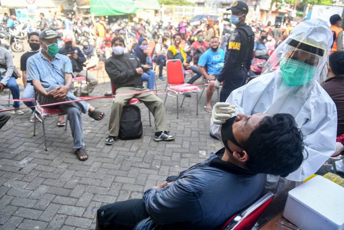ANTARA FOTO/M Risyal Hidayat Seorang tenaga kesehatan yang mengenakan alat pelindung diri lengkap melakukan tes usap (swab test) COVID-19 pada warga