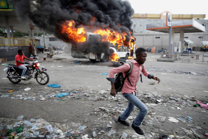 REUTERS/Andres Martinez Casares Seorang pria berlari melewati bus yang terbakar
