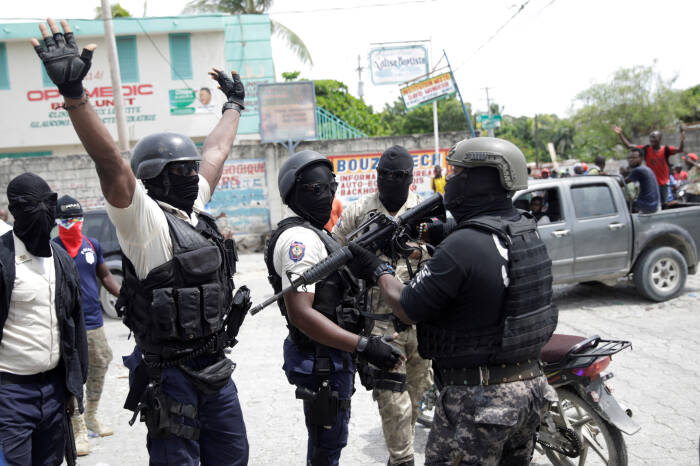 Para pengunjuk rasa berseragam polisi mengangkat tangan mereka saat mereka menghadapi petugas Kepolisian Nasional Haiti (PNH) yang sedang bertugas memegang senapan selama protes (REUTERS/Andres Martinez Casares) Para pengunjuk rasa berseragam polisi mengangkat tangan mereka saat mereka menghadapi petugas Kepolisian Nasional Haiti (PNH) yang sedang bertugas memegang senapan selama protes