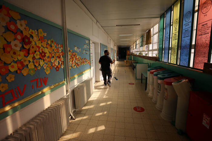 REUTERS/Ammar Awad Seorang pria membersihkan sekolah yang ditutup