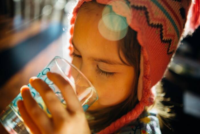 Ilustrasi anak minum air putih (Unsplash/@johnnymcclung) cara menghilangkan panas anak minum air putih banyak