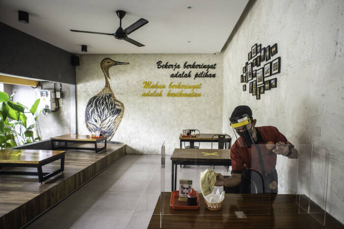 Pramusaji membersihkan mika pembatas meja makan di restoran Bebek Kaleyo, Kemanggisan, Jakarta, Senin (12/10/2020). ANTARA FOTO/Aprillio Akbar Pramusaji membersihkan mika pembatas meja makan di restoran Bebek Kaleyo, Kemanggisan, Jakarta, Senin (12/10/2020). ANTARA FOTO/Aprillio Akbar