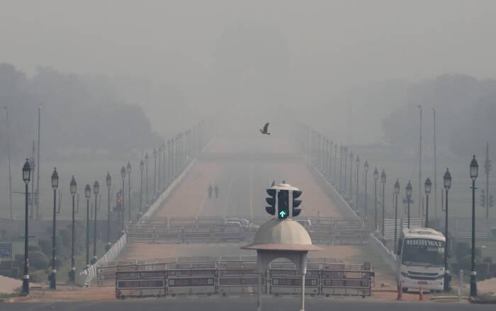 REUTERS/Anushree Fadnavis Orang-orang berjalan di dekat Gerbang India pada pagi yang berkabut di New Delhi
