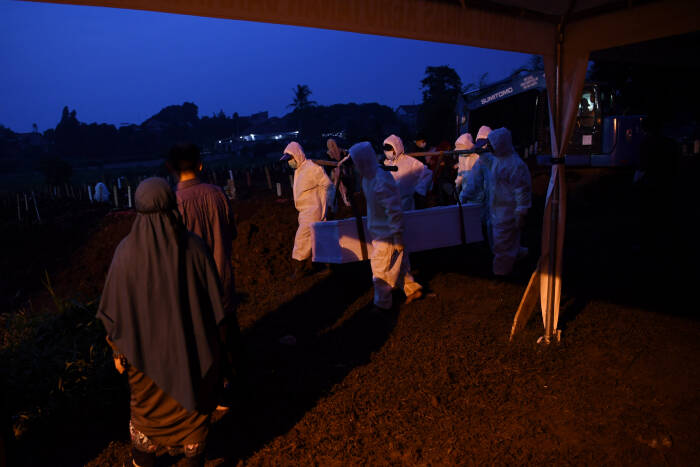 ANTARA FOTO/Wahyu Putro A Petugas yang mengenakan APD bersiap membawa peti berisi jenazah dengan protokol COVID-19 di TPU Srengseng Sawah