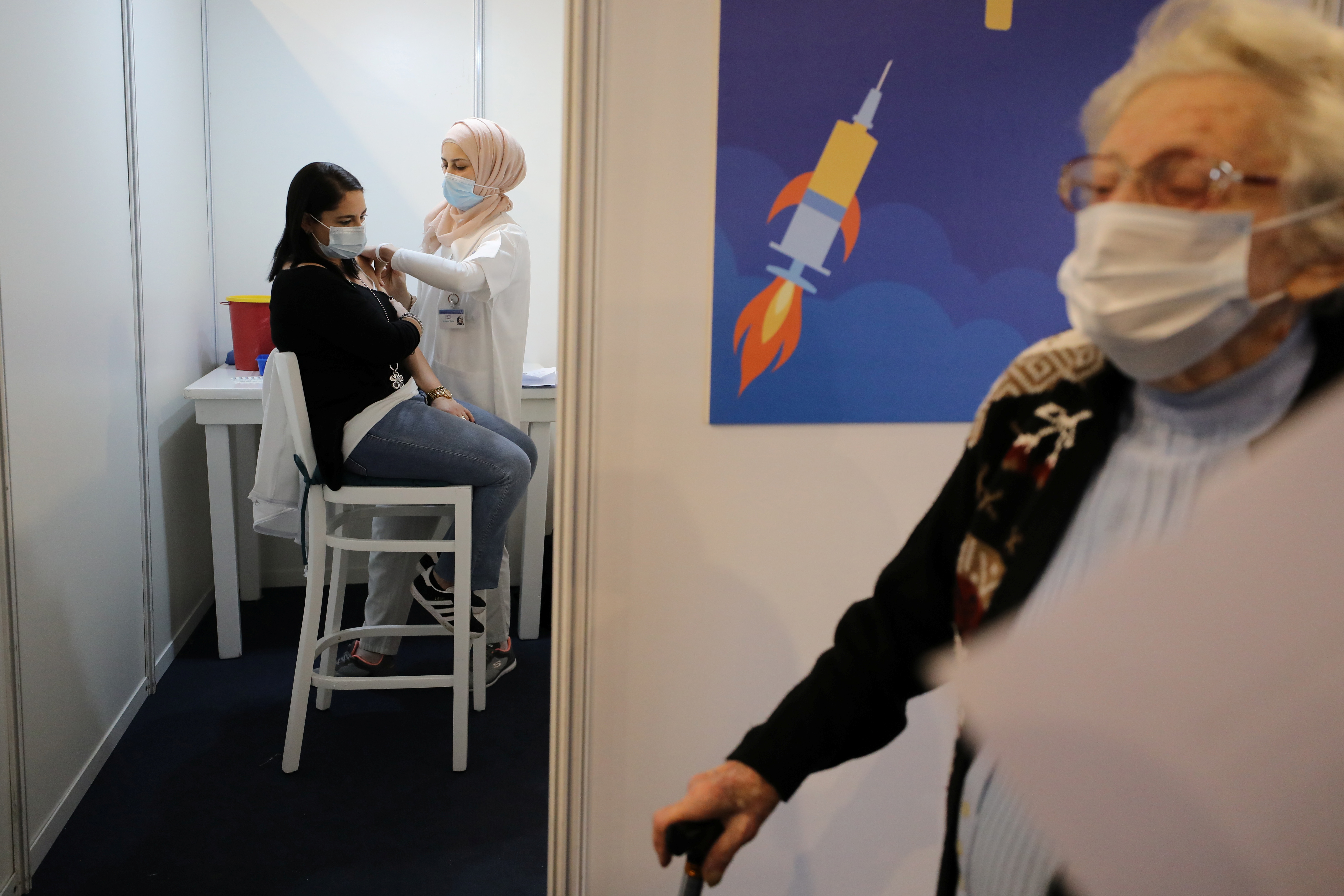 Seorang petugas kesehatan memberikan vaksin Covid-19 kepada seorang wanita dalam vaksinasi nasional Isreal di Kota Tel Aviv pada Kamis (31/12). (REUTERS/Ammar Awad) vaksinasi covid-19 di israel