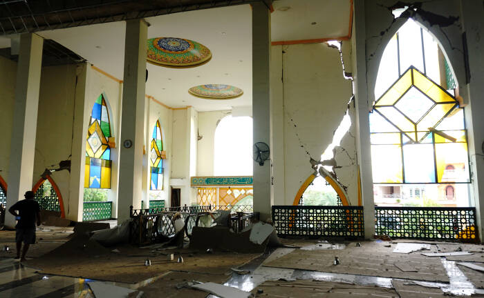 ANTARA FOTO / Akbar Tado Seorang warga melintas di puing bangunan Masjid Agung Suhada yang roboh di Mamuju